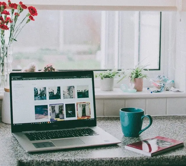 Kitchen office with a laptop, a cup of beverage, and a book